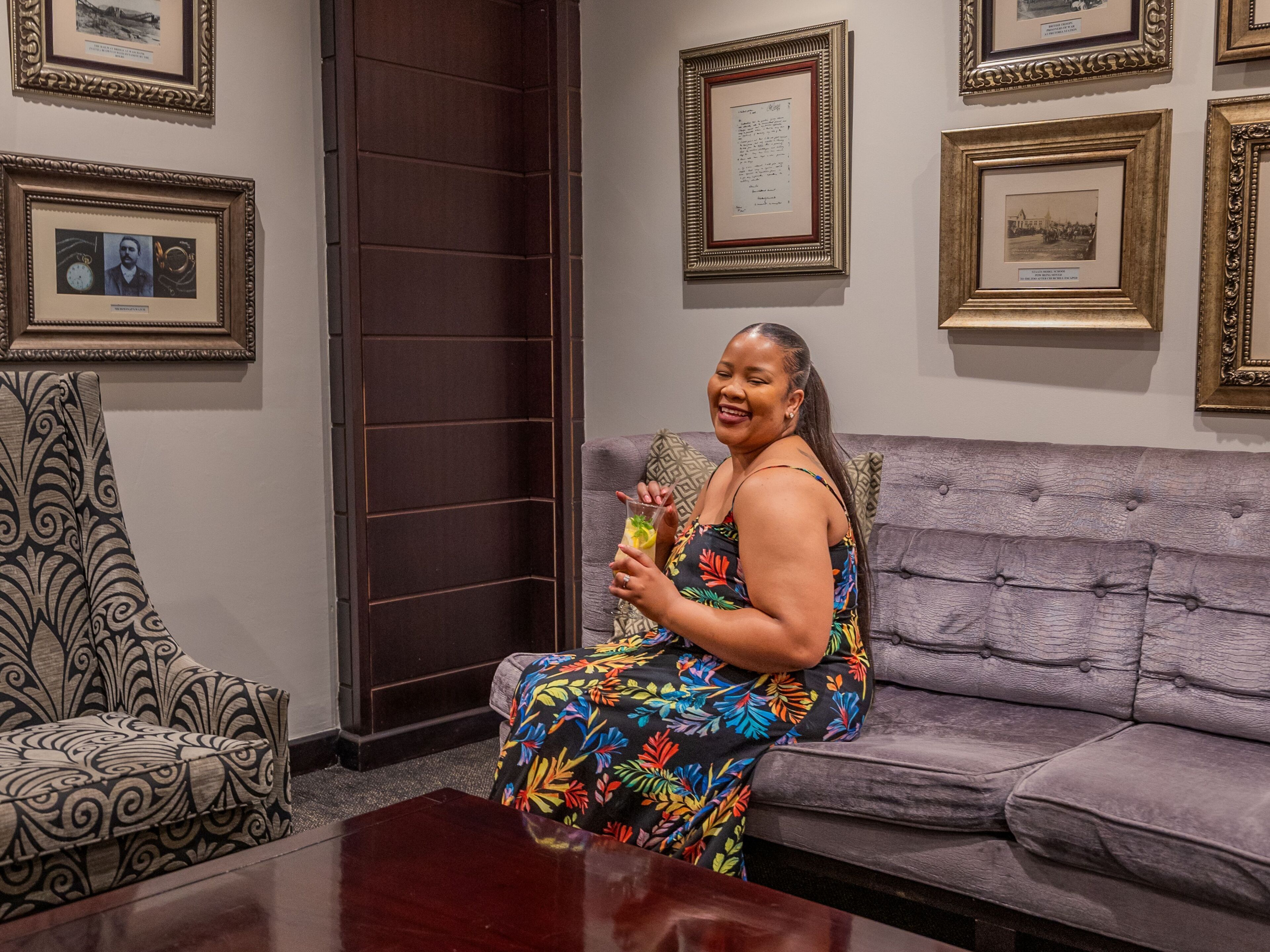 A woman sitting on a sofa in a room with framed pictures on the wall.