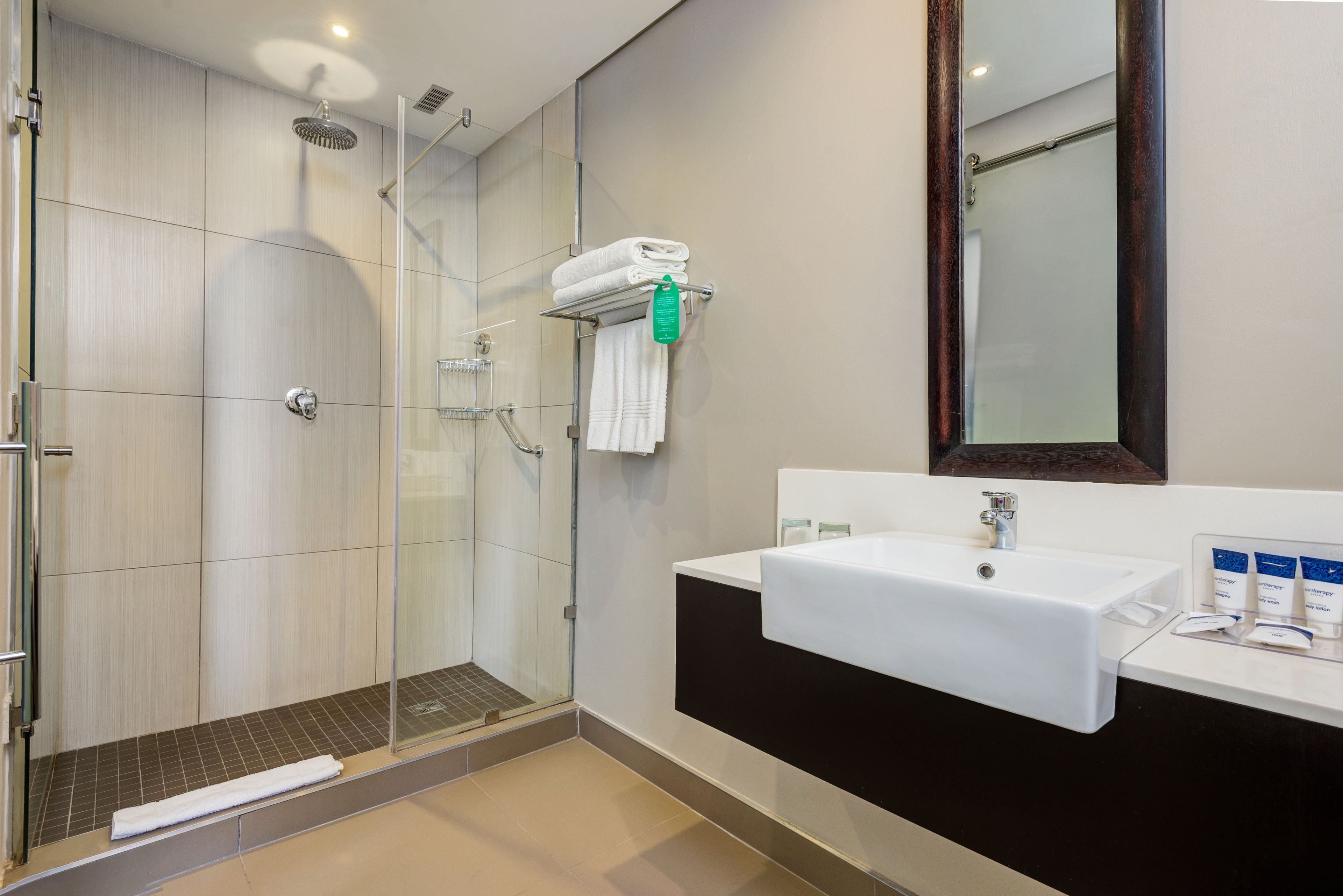 A modern bathroom with a glass-enclosed shower, a white sink, and a large mirror.