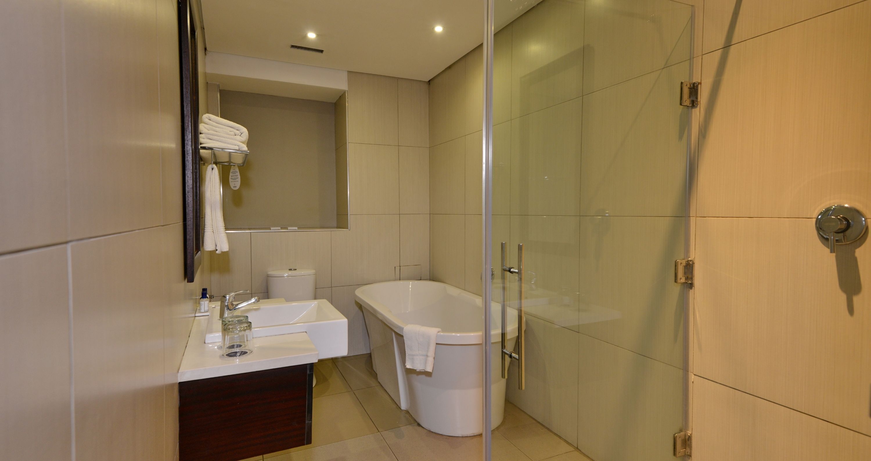 A modern bathroom with a glass-enclosed shower, a white bathtub, and a vanity with a mirror and sink.