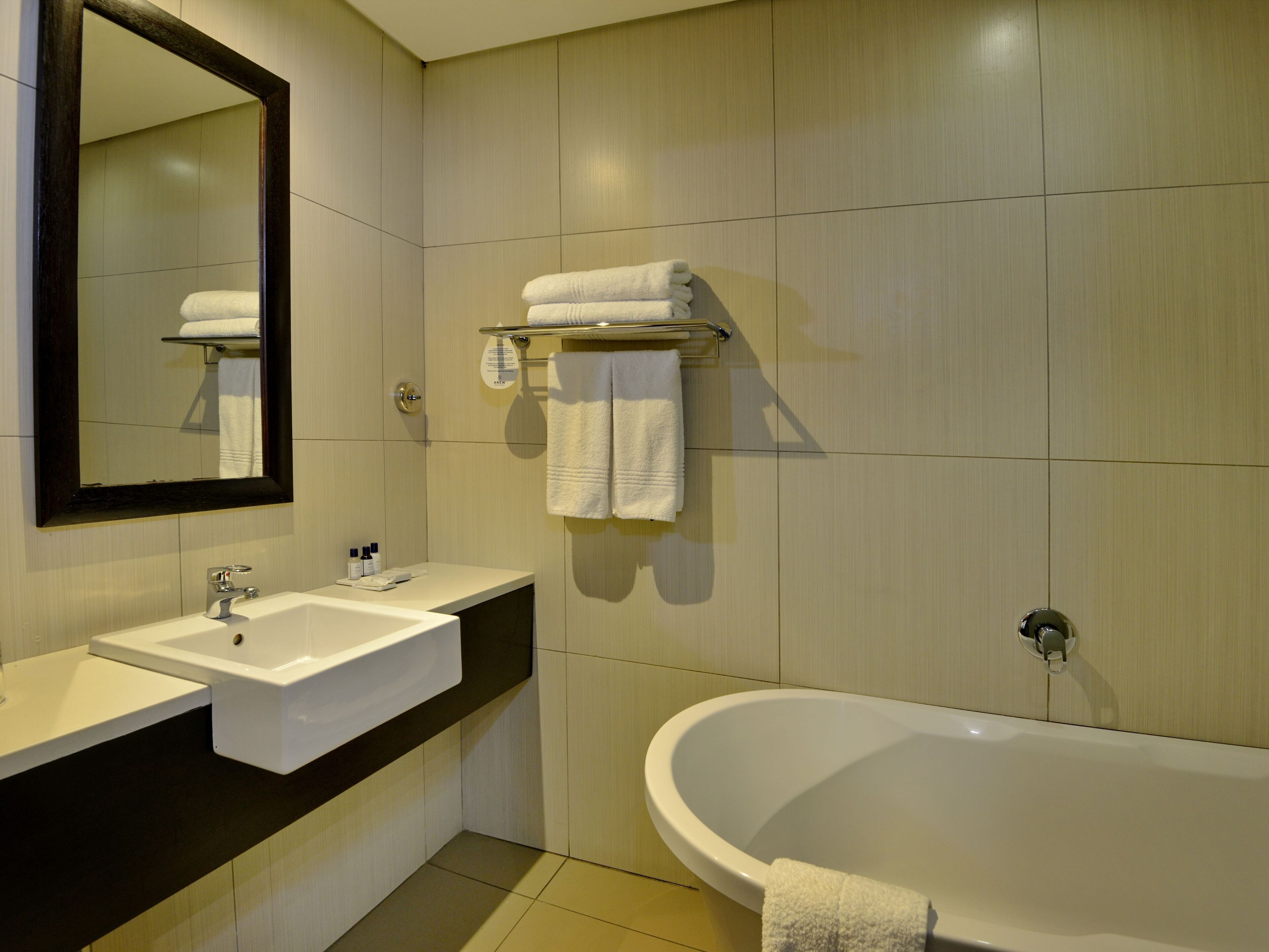 A modern bathroom with a large bathtub, a double sink vanity, and a mirror.