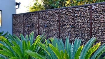 Una pared con textura de piedra y una valla metálica.