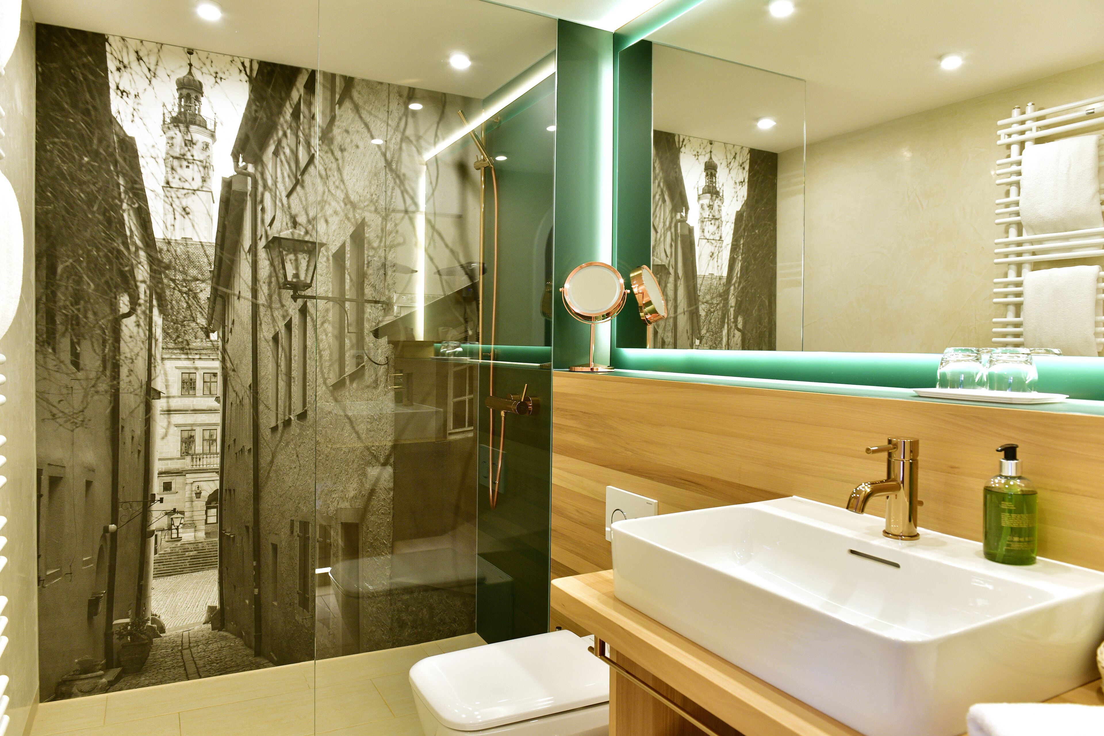 A modern bathroom with a large mirror, a white sink, and a glass-enclosed shower.