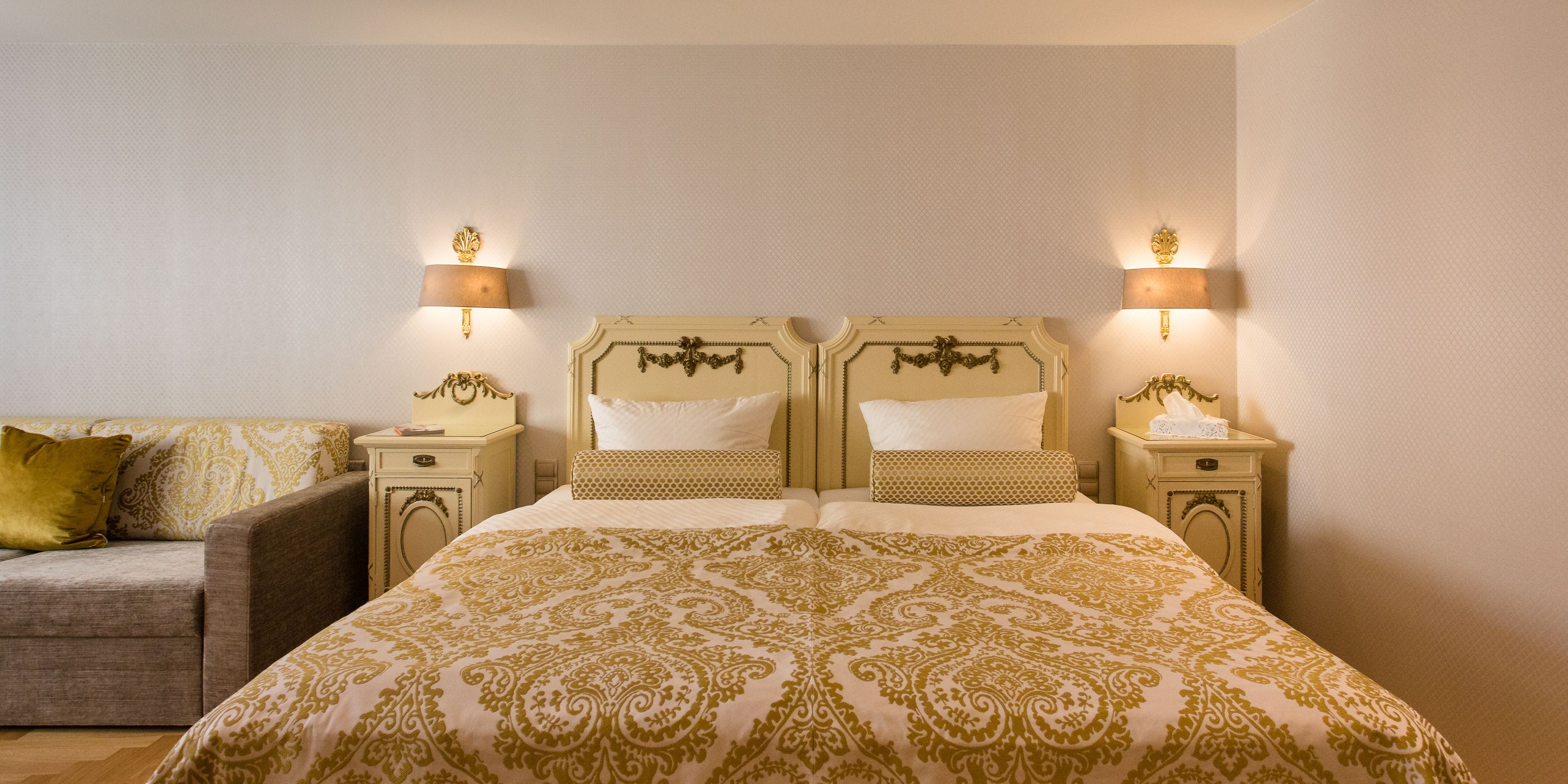 Una habitación de hotel con una cama grande, dos mesitas de noche y un sofá.