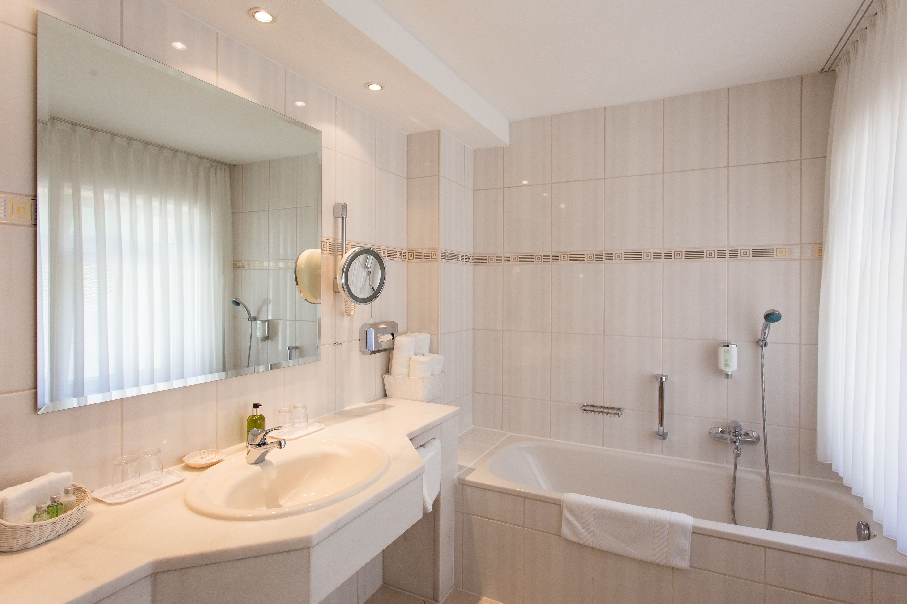 A modern bathroom with a large sink, mirror, and bathtub.