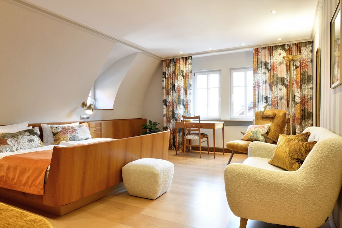 Un dormitorio moderno con cama tipo altillo, un escritorio de madera y un sillón cómodo.