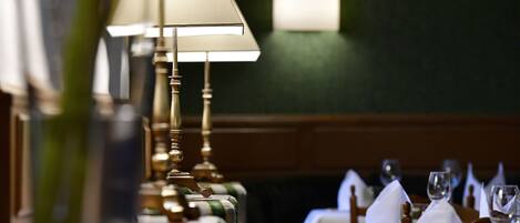 A restaurant setting with tables set for dining, featuring lamps and neatly arranged napkins.