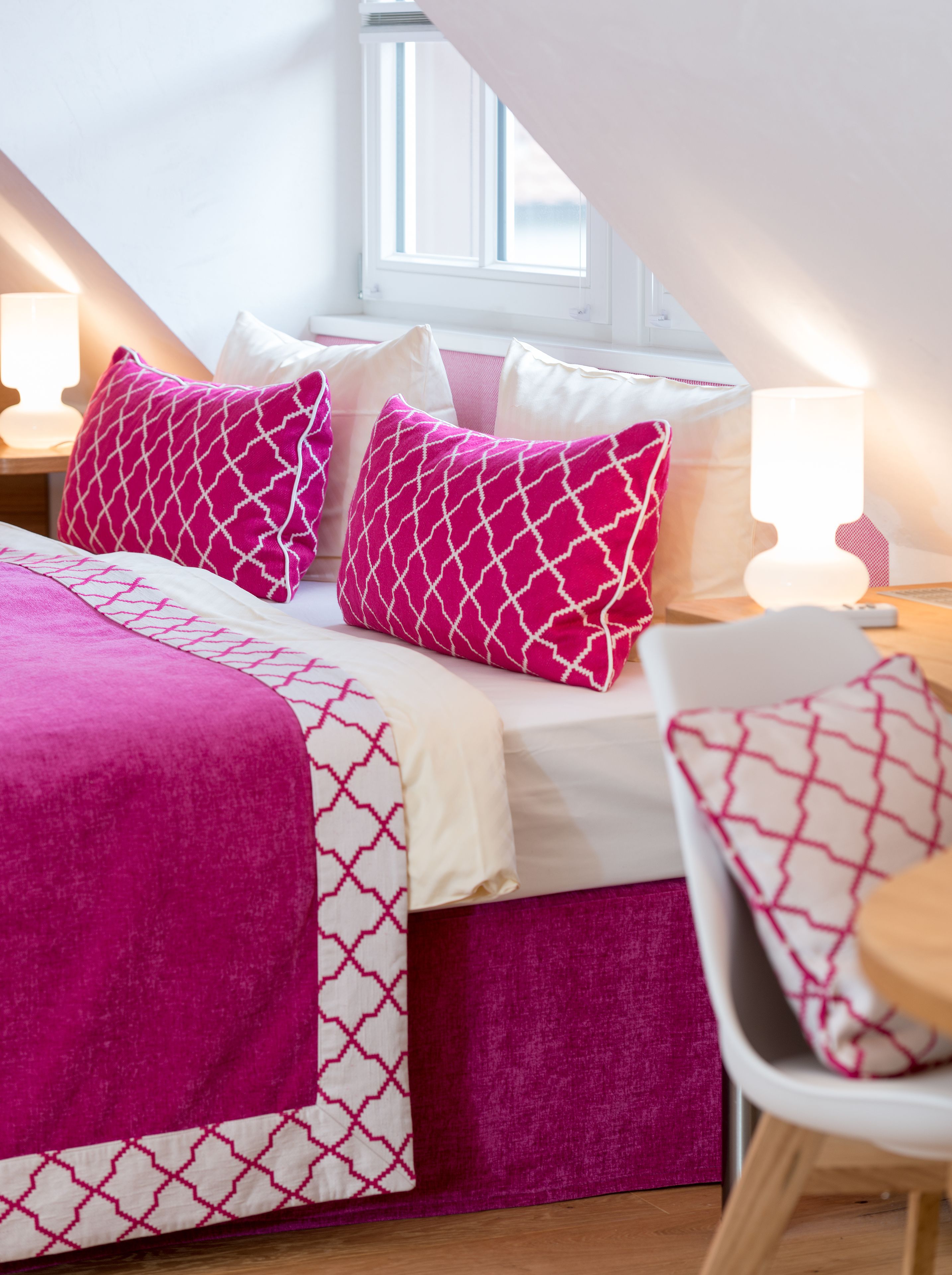 A bedroom with a bed, pillows, and a chair.