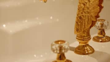 A bathroom with a gold faucet and a gold towel rack.