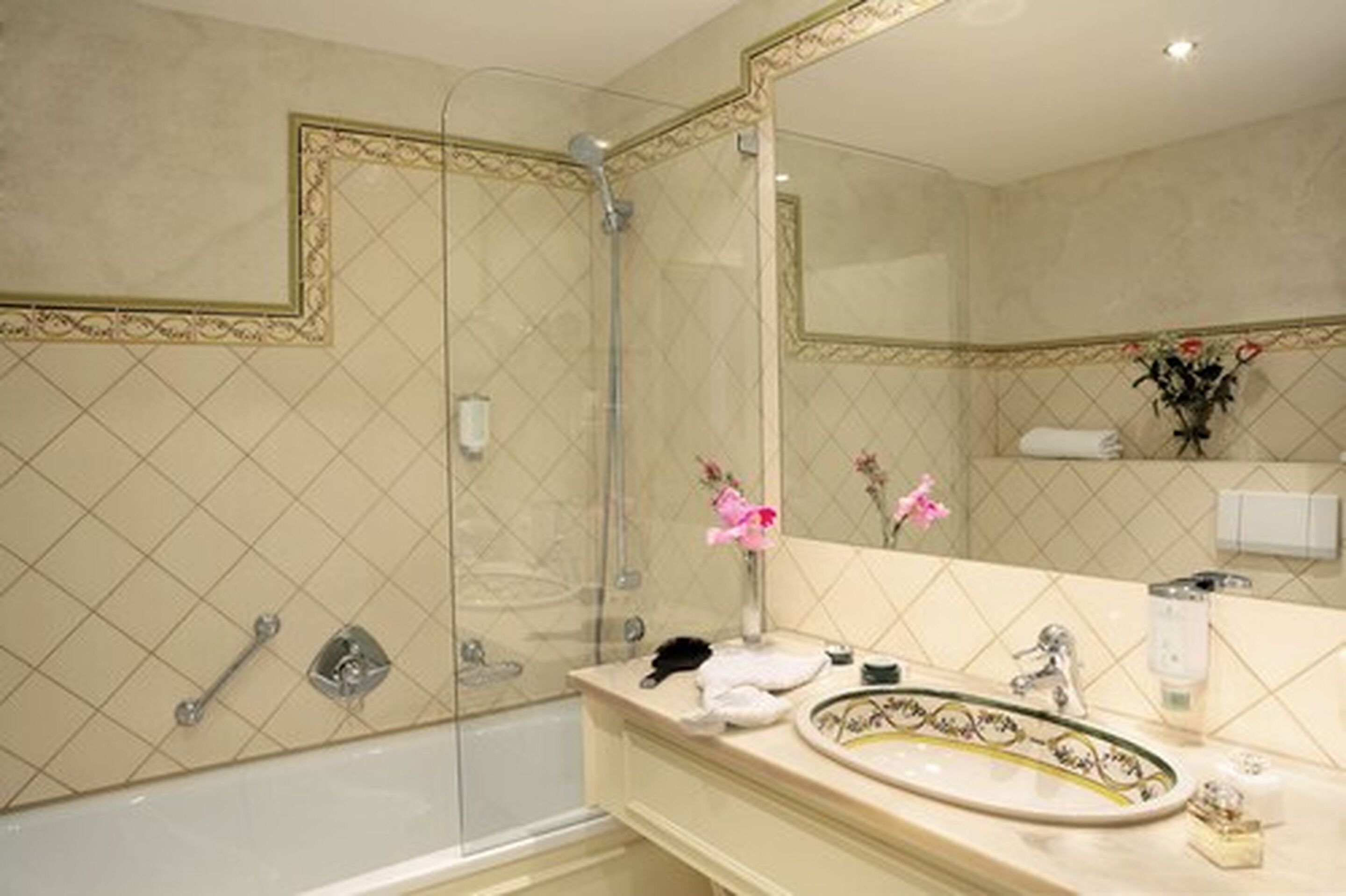 A bathroom with a large mirror, a bathtub, a shower, and a vanity with a sink and towel rack.