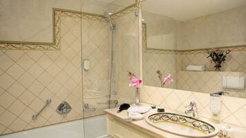 A bathroom with a large mirror, a bathtub, a shower, and a vanity with a sink and towel rack.