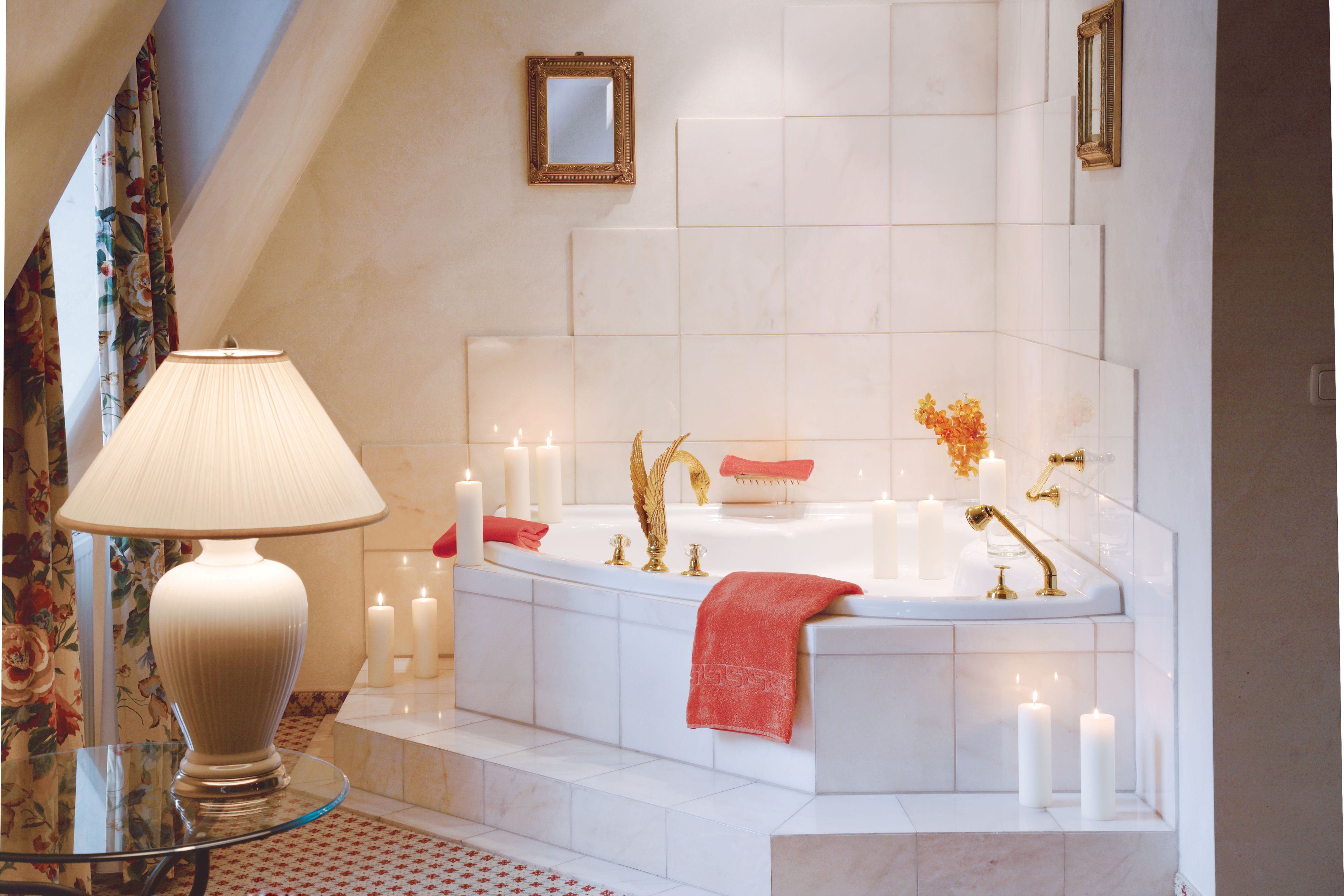 Ein Badezimmer mit einer Badewanne, Kerzen, einem Glastisch und einem Spiegel an der Wand.