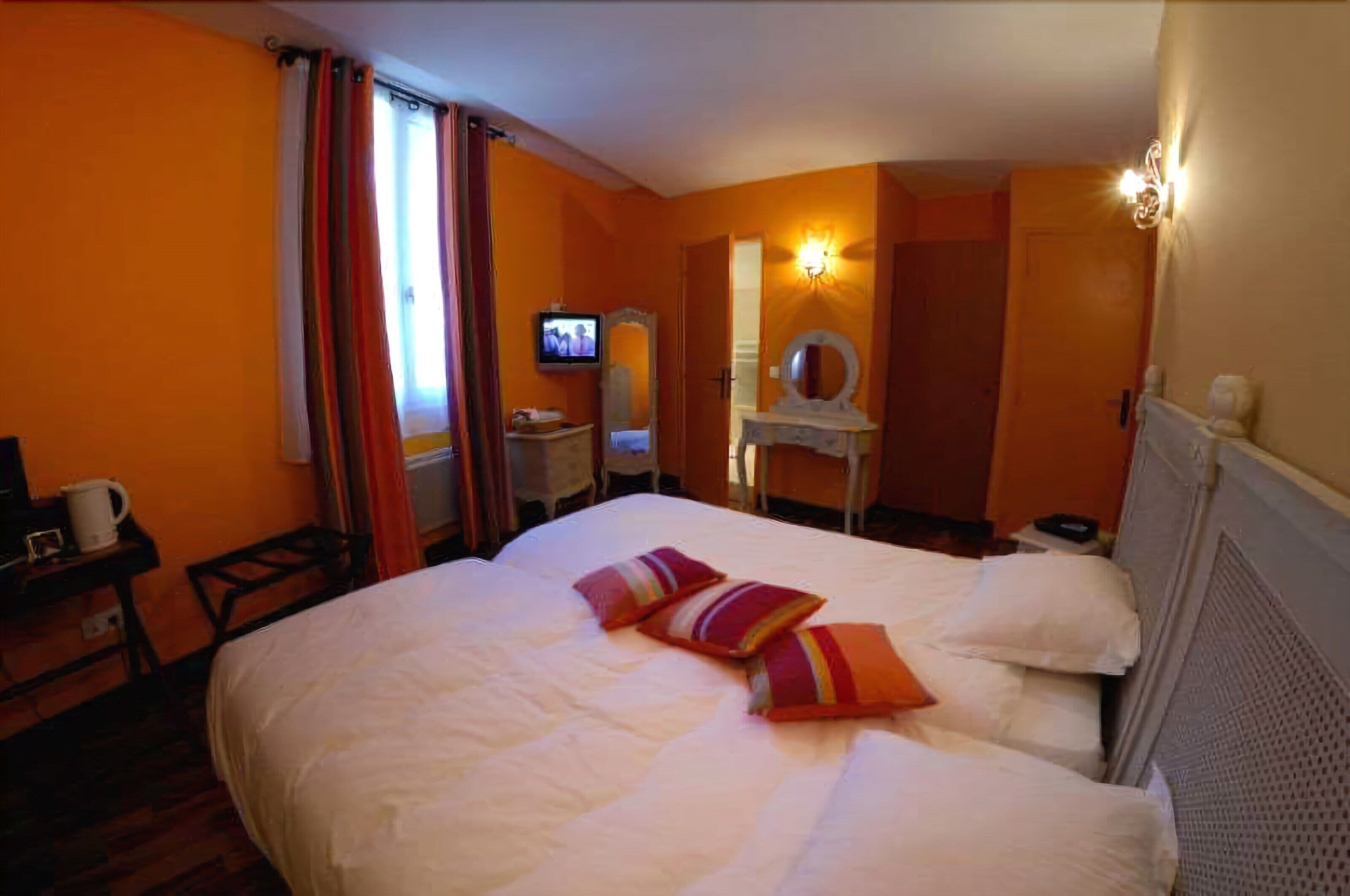 Une chambre d’hôtel comprenant un lit, une télévision, un bureau avec une chaise et un miroir.