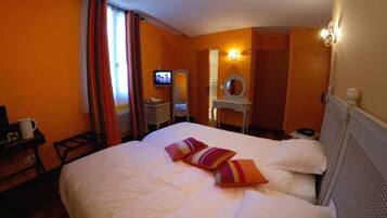 Une chambre d’hôtel comprenant un lit, une télévision, un bureau avec une chaise et un miroir.