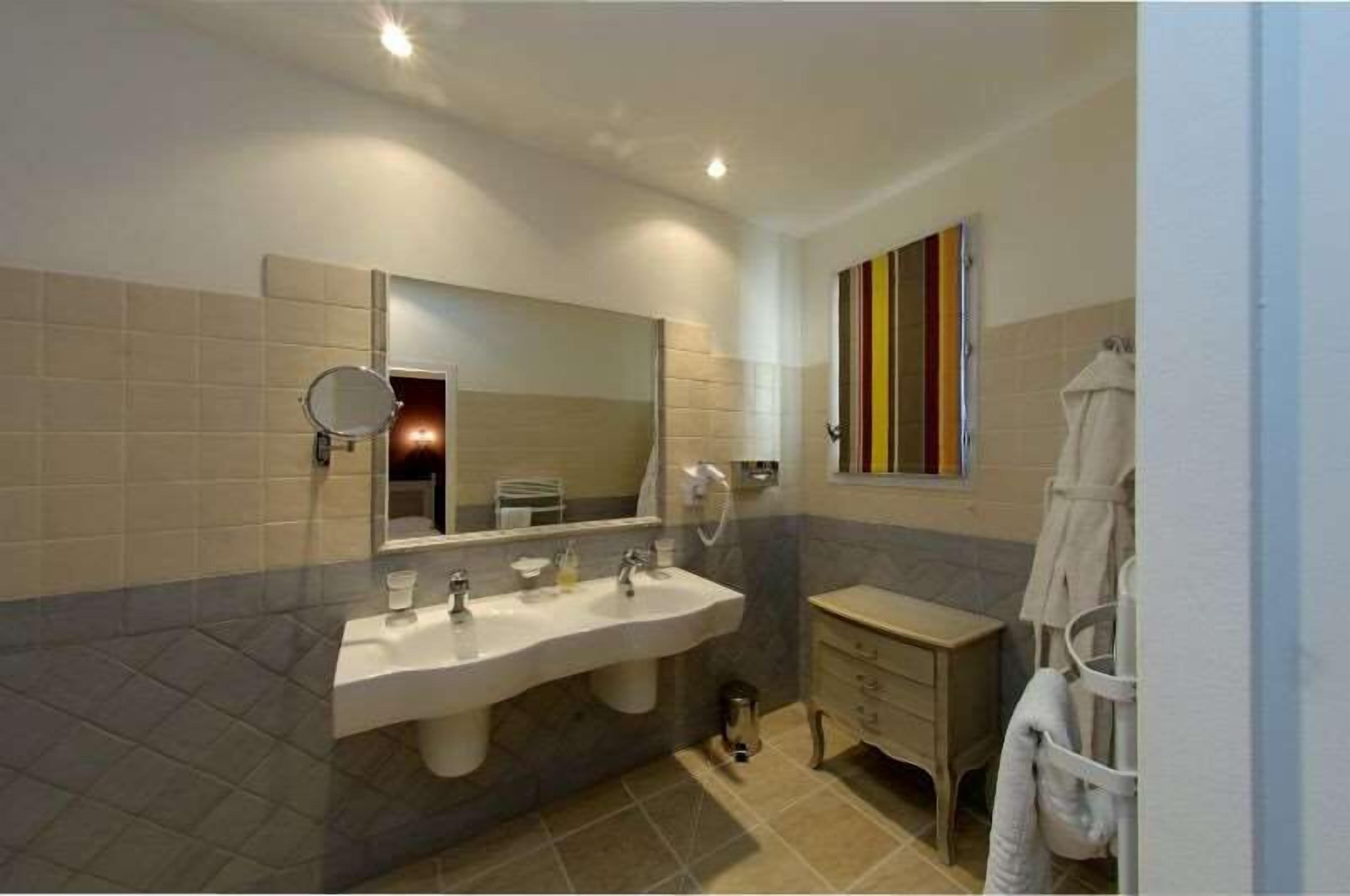 A modern bathroom with two sinks, a large mirror, and a towel rack.