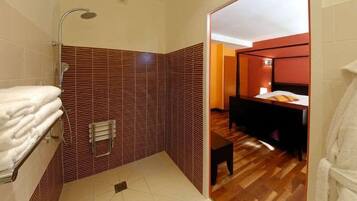 A bathroom with a shower, a towel rack, and a wooden floor.