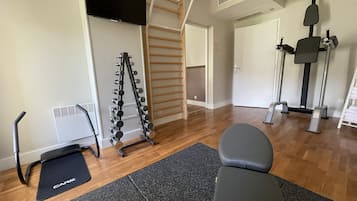 A home gym with a treadmill, weight bench, and a pull-up bar.