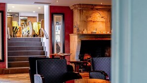 Een hotellobby met een open haard, een zithoek en een trap naar een ander niveau.