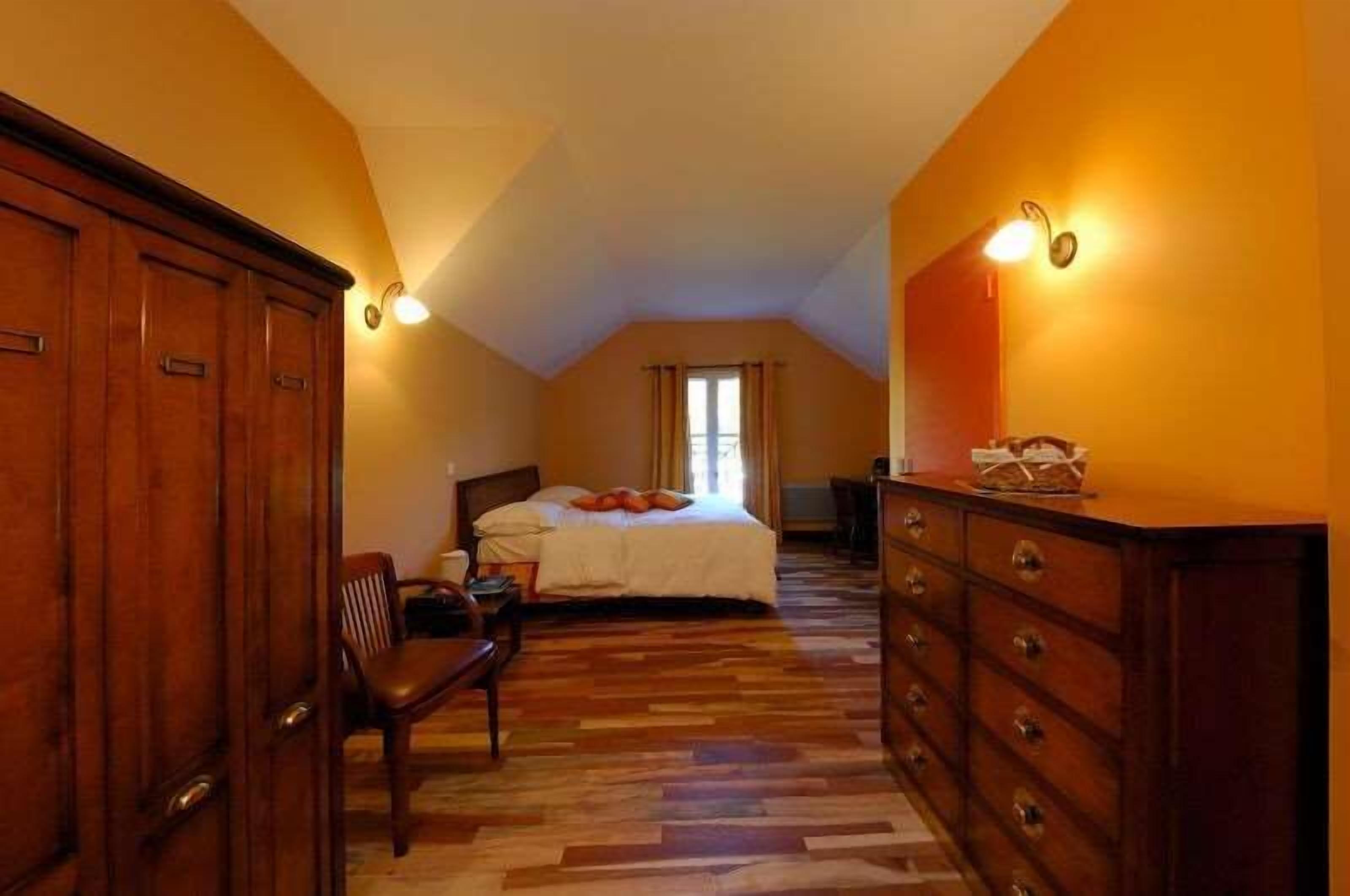 A bedroom with a large bed, wooden dresser, and a chair.