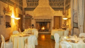 A dining area with tables set for a meal, a fireplace, and classical wall decorations.