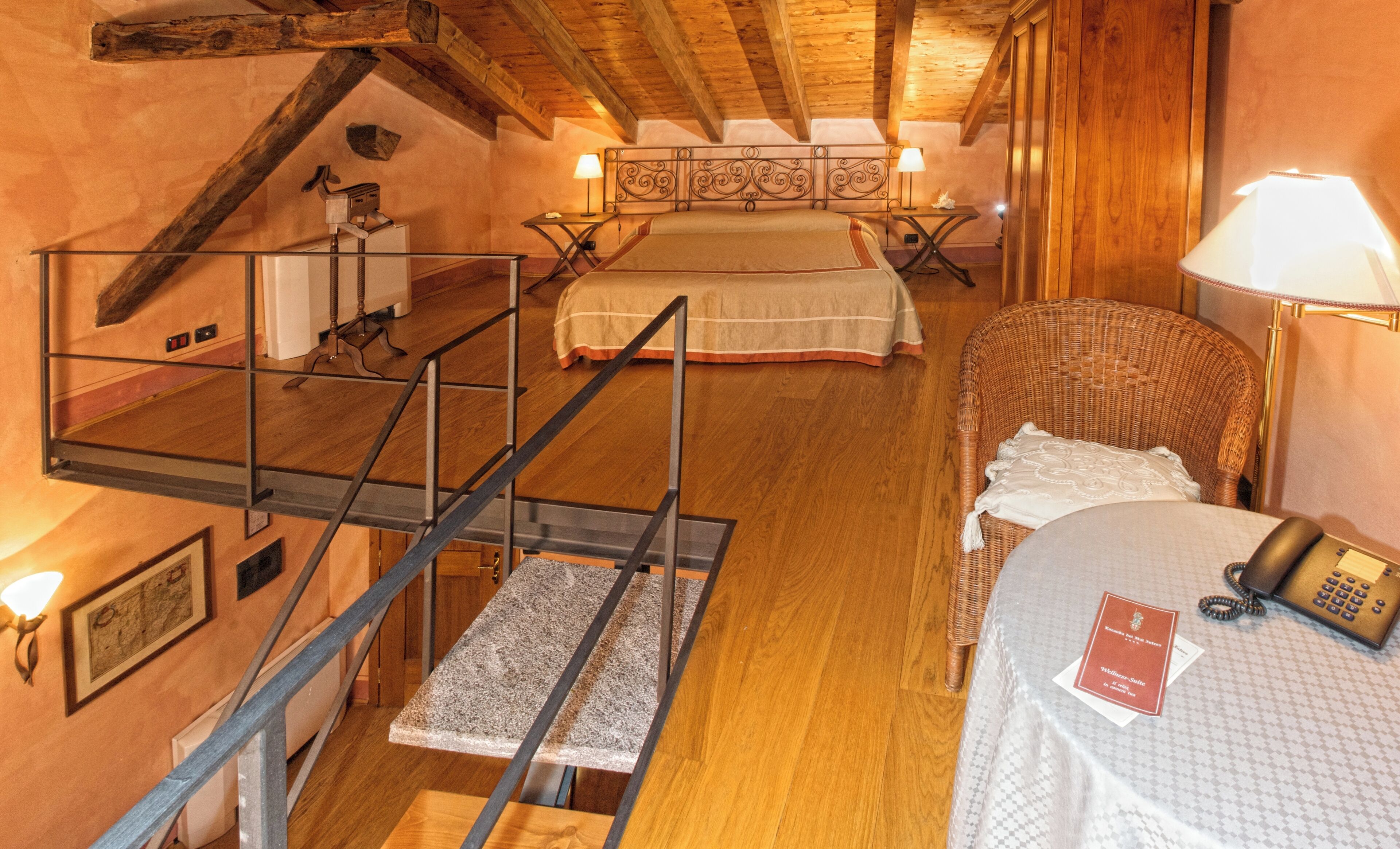A bedroom with a bunk bed, a chair, a desk with a lamp, and a telephone.