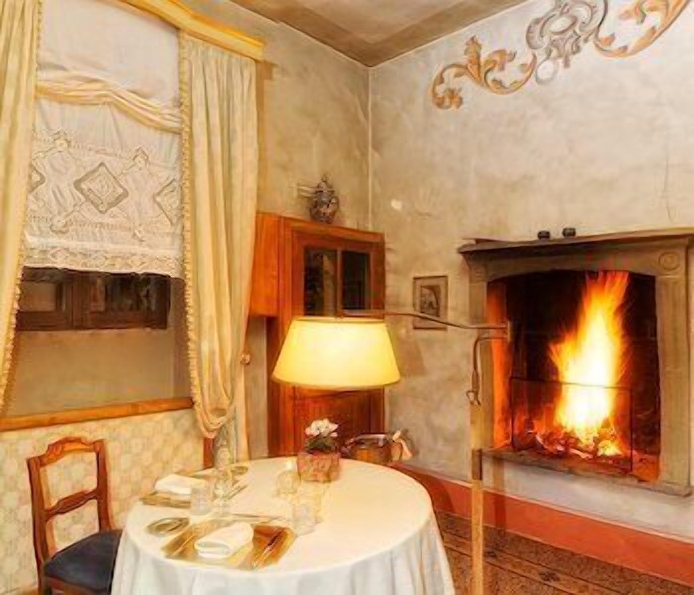 A dining room with a fireplace, a table set for two, and a lamp.