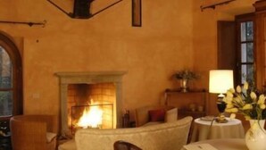 A cozy room with a fireplace, a sofa, a table with a lamp, and a vase of flowers.