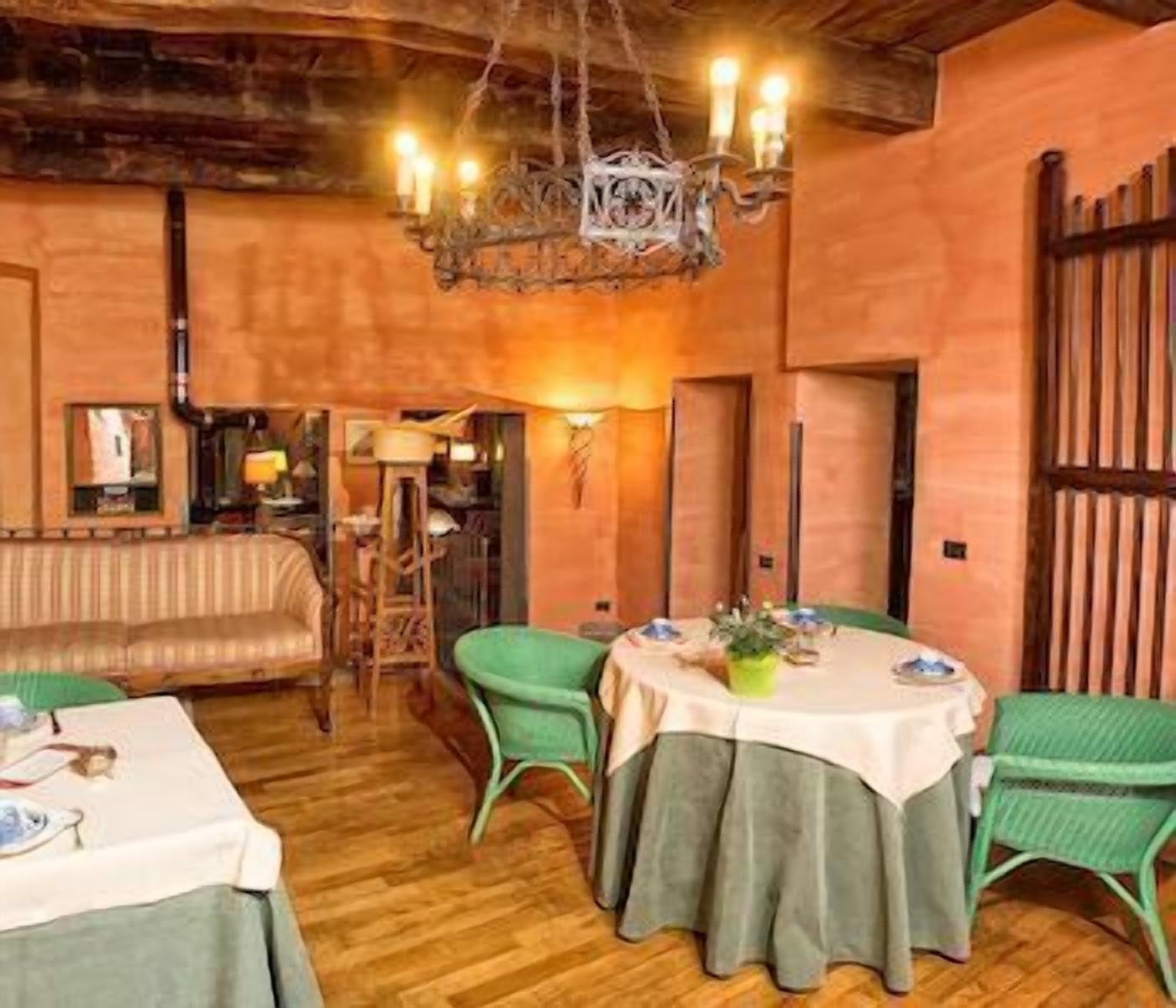 A cozy dining area with a round table, green chairs, and a chandelier.