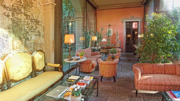 A lobby with a sofa, armchairs, a coffee table, and a large plant.