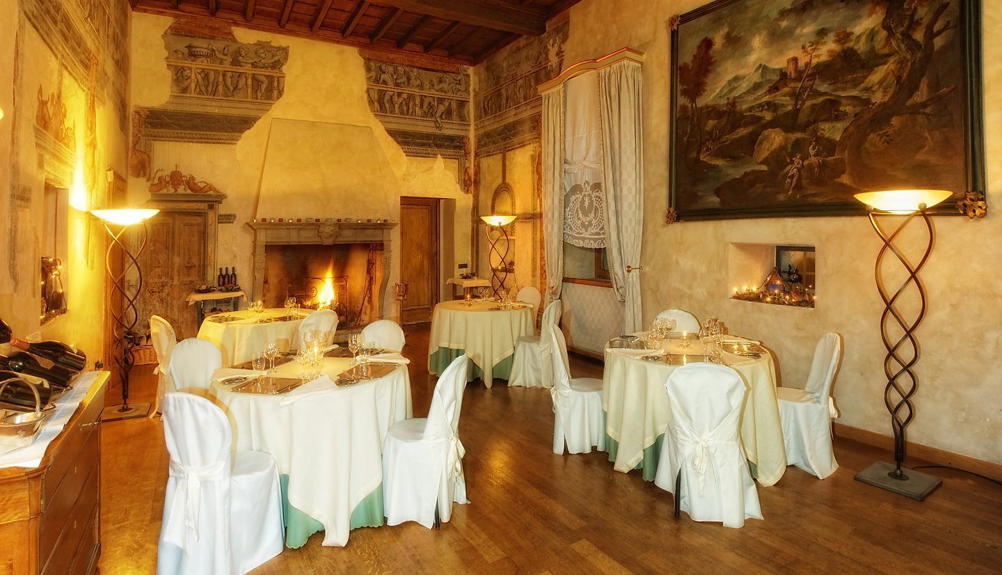 Comedor con mesas redondas, sillas blancas y una chimenea.
