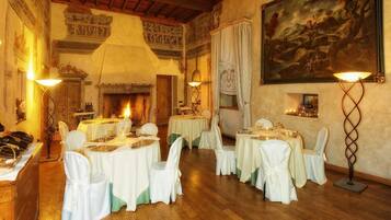 Comedor con mesas redondas, sillas blancas y una chimenea.