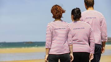 Three people walking on a beach wearing matching striped shirts.