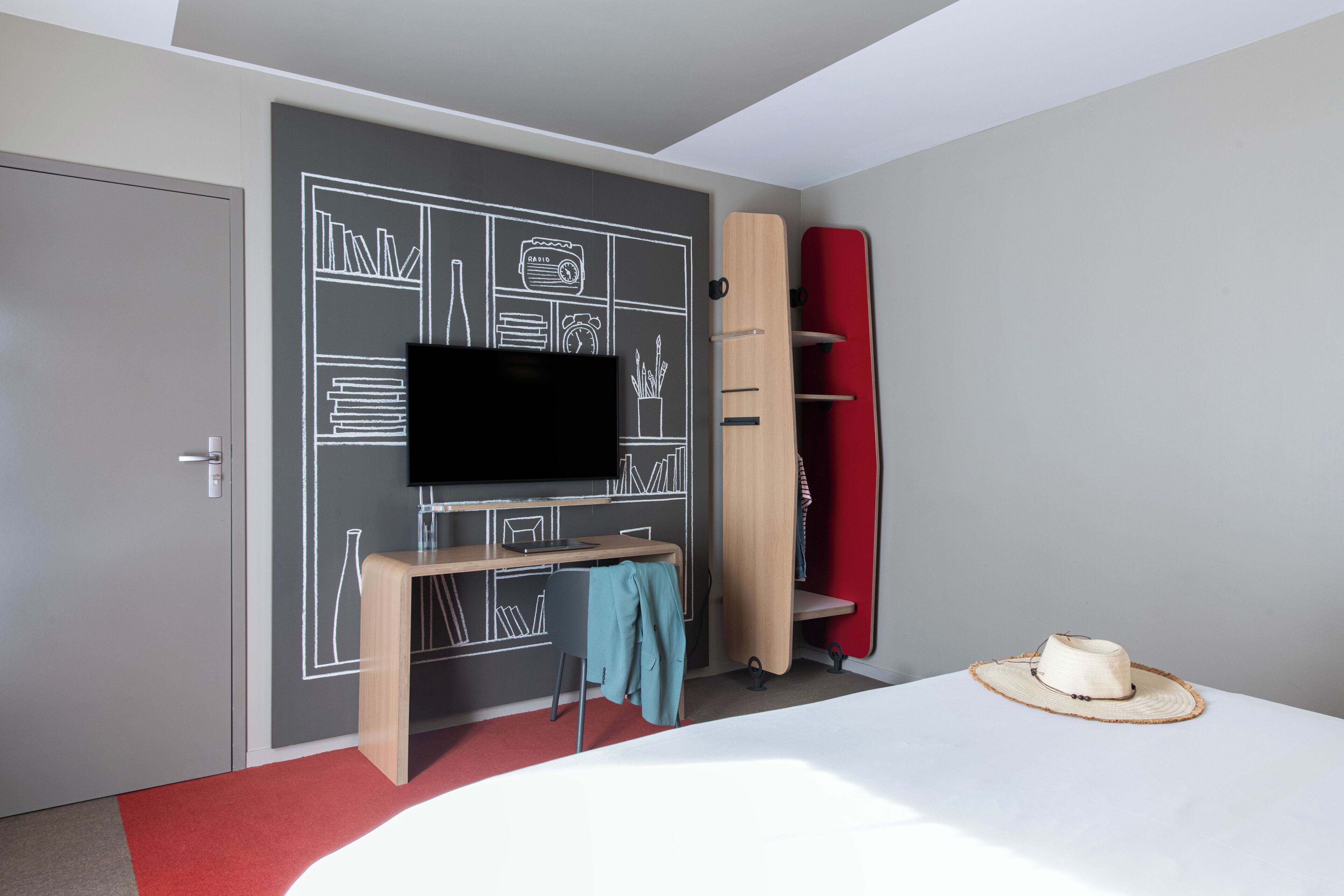 Une chambre à coucher comprenant un lit, un bureau, une chaise, un téléviseur, une bibliothèque et une planche de surf.
