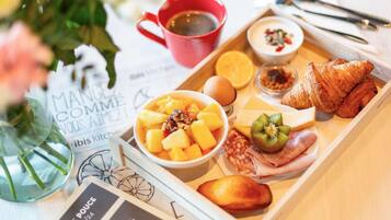 Una bandeja con alimentos, entre ellos frutas, un croissant y una bebida.
