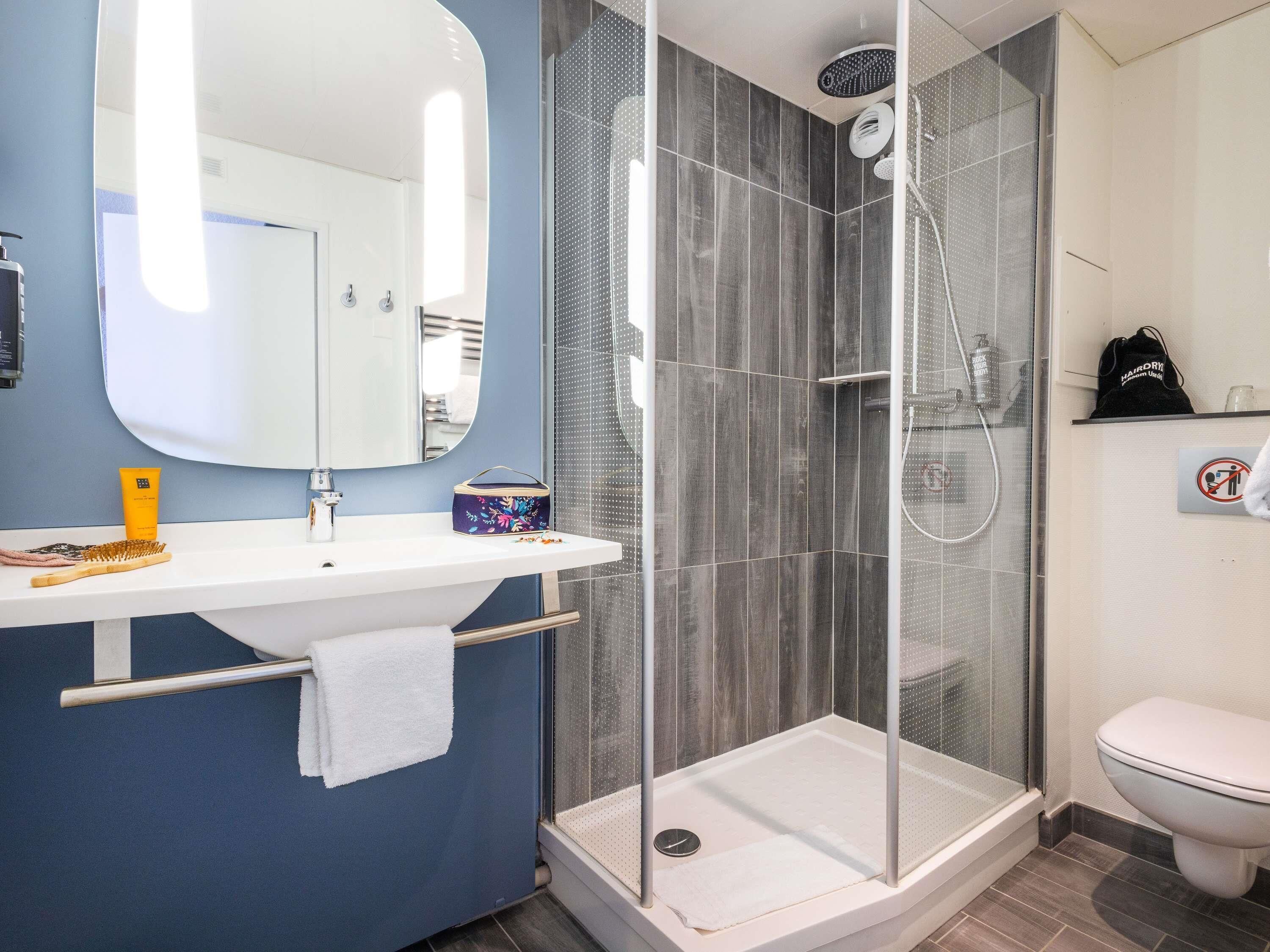 A modern bathroom with a shower enclosure, a sink with a mirror, and a toilet.