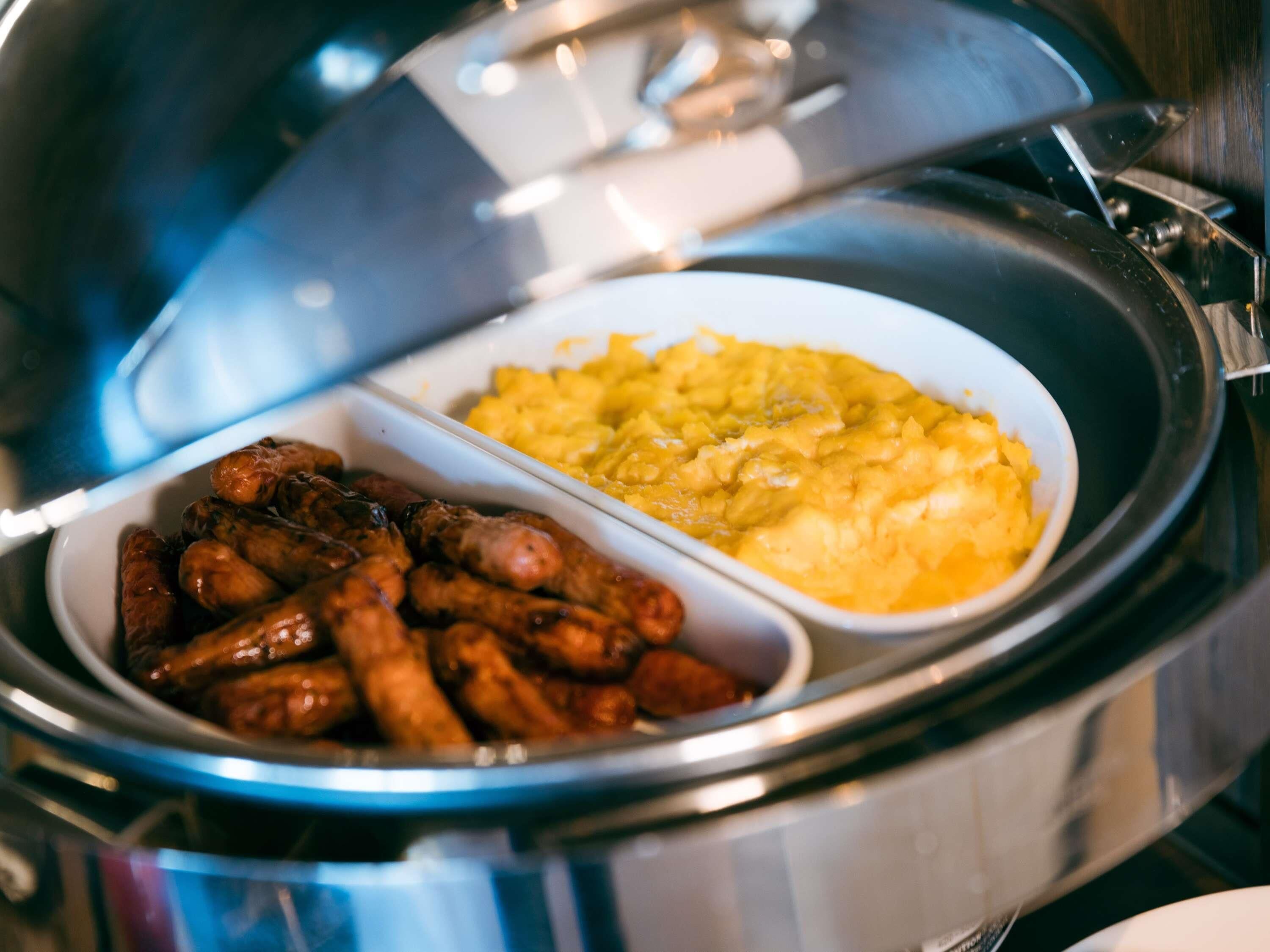 A buffet with two dishes: sausages and mashed potatoes.