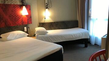 A hotel room with two beds, a red carpet, a red chair, and a window with curtains.