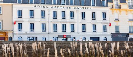 Un edificio con el letrero "HOTEL JACQUES CARTIER" y una fila de postes de madera al frente.