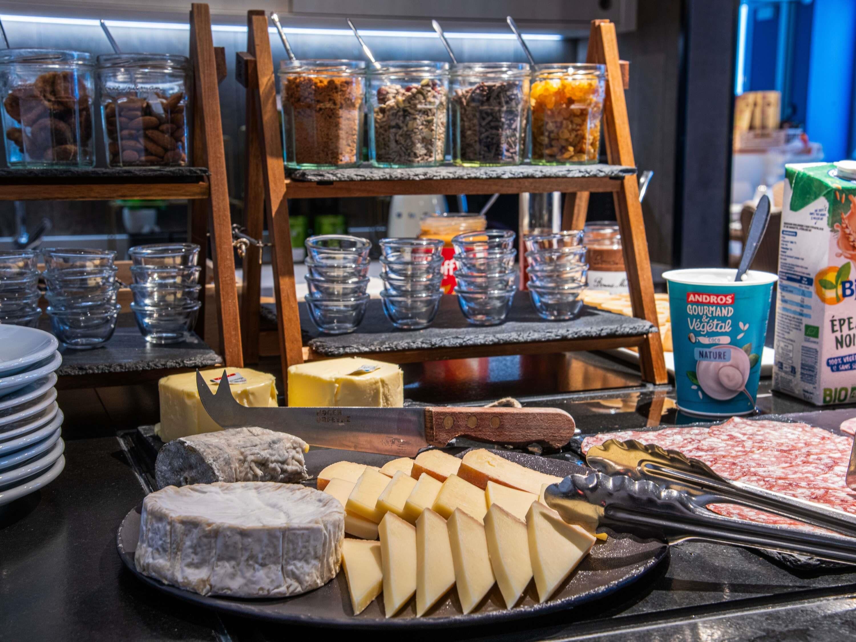 A cheese and yogurt display with various cheeses and a carton of yogurt.