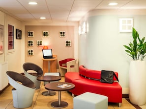 A modern interior with a red sofa, two chairs, a small table, a laptop, and a potted plant. - ibis Massy (Massy)