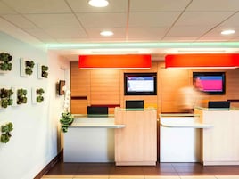 Un área de recepción con dos mostradores, paneles de madera y una pantalla grande mostrando contenido.