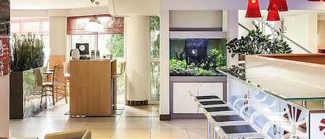 A hotel lobby with a reception desk, seating area, and a large aquarium.