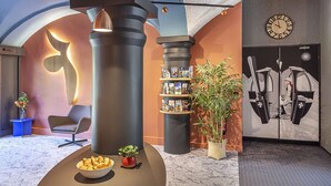 Eine moderne Lobby mit einer großen Säule, einer Uhr, einem Empfangstresen und einer Wand mit grafischem Design.