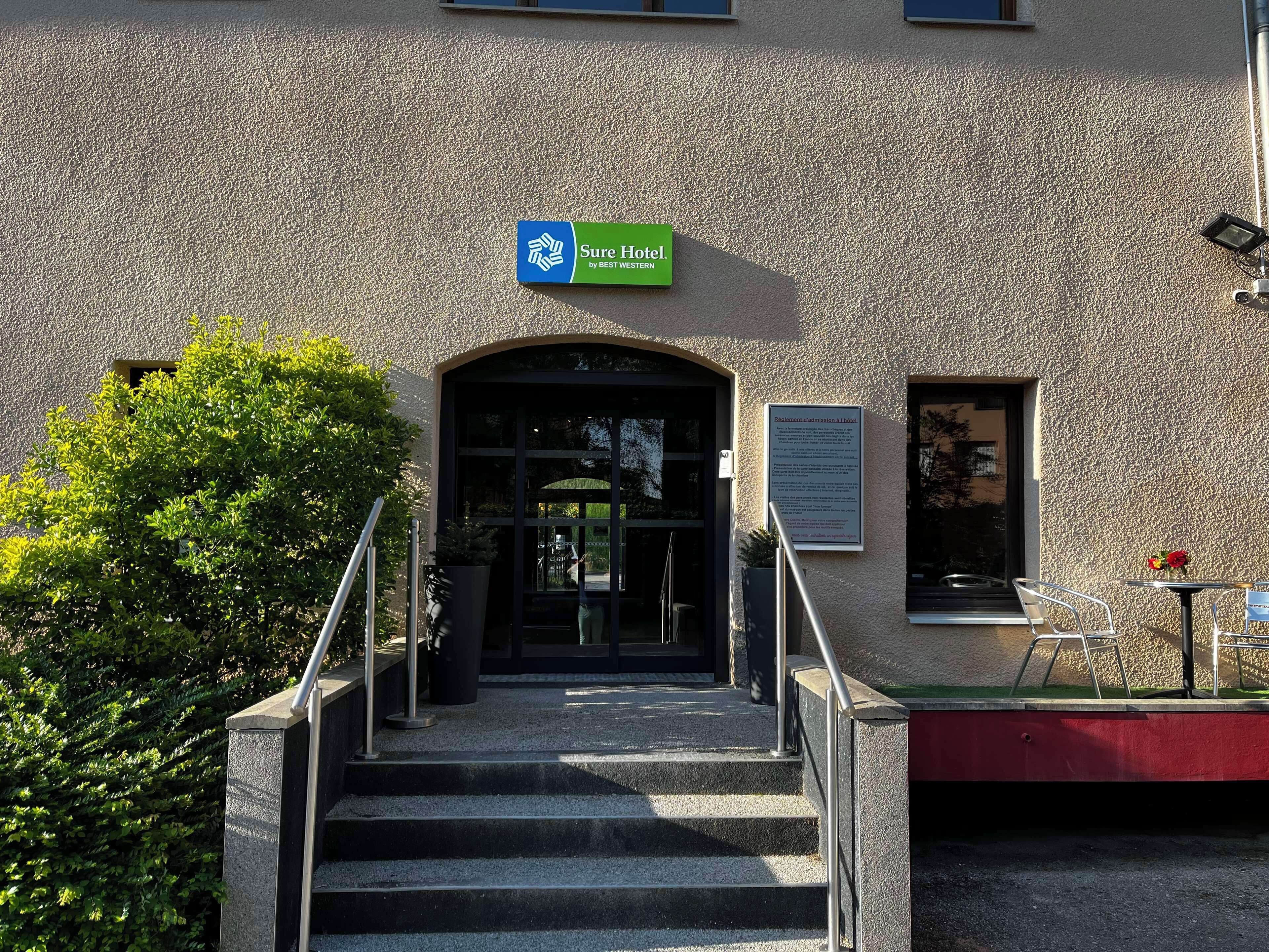 A hotel entrance with a sign reading "Sure Hotel by BEST WESTERN" and a sign indicating "Admission Required".