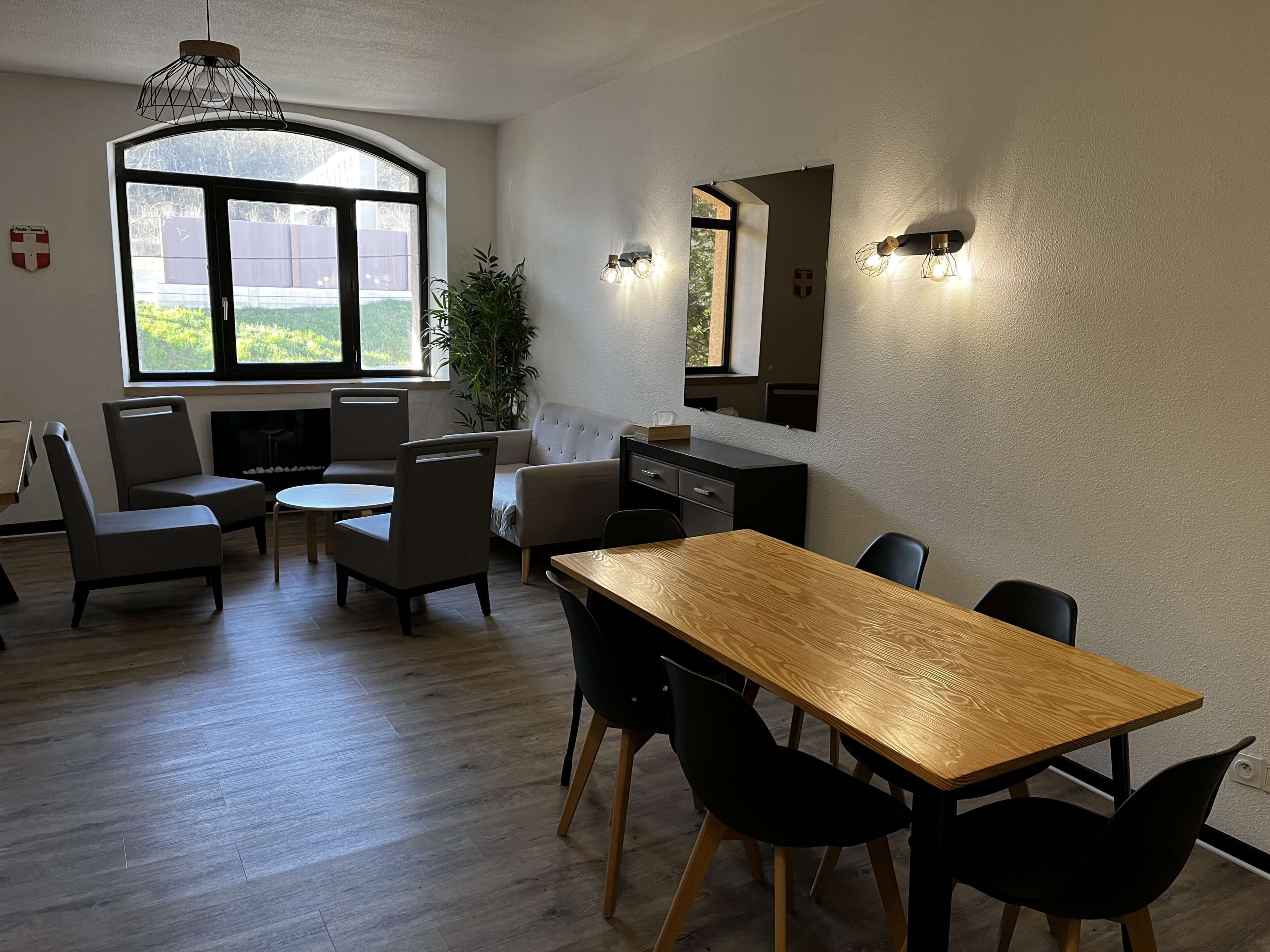 Een moderne eetruimte met een houten tafel en stoelen, een bank en een potplant.