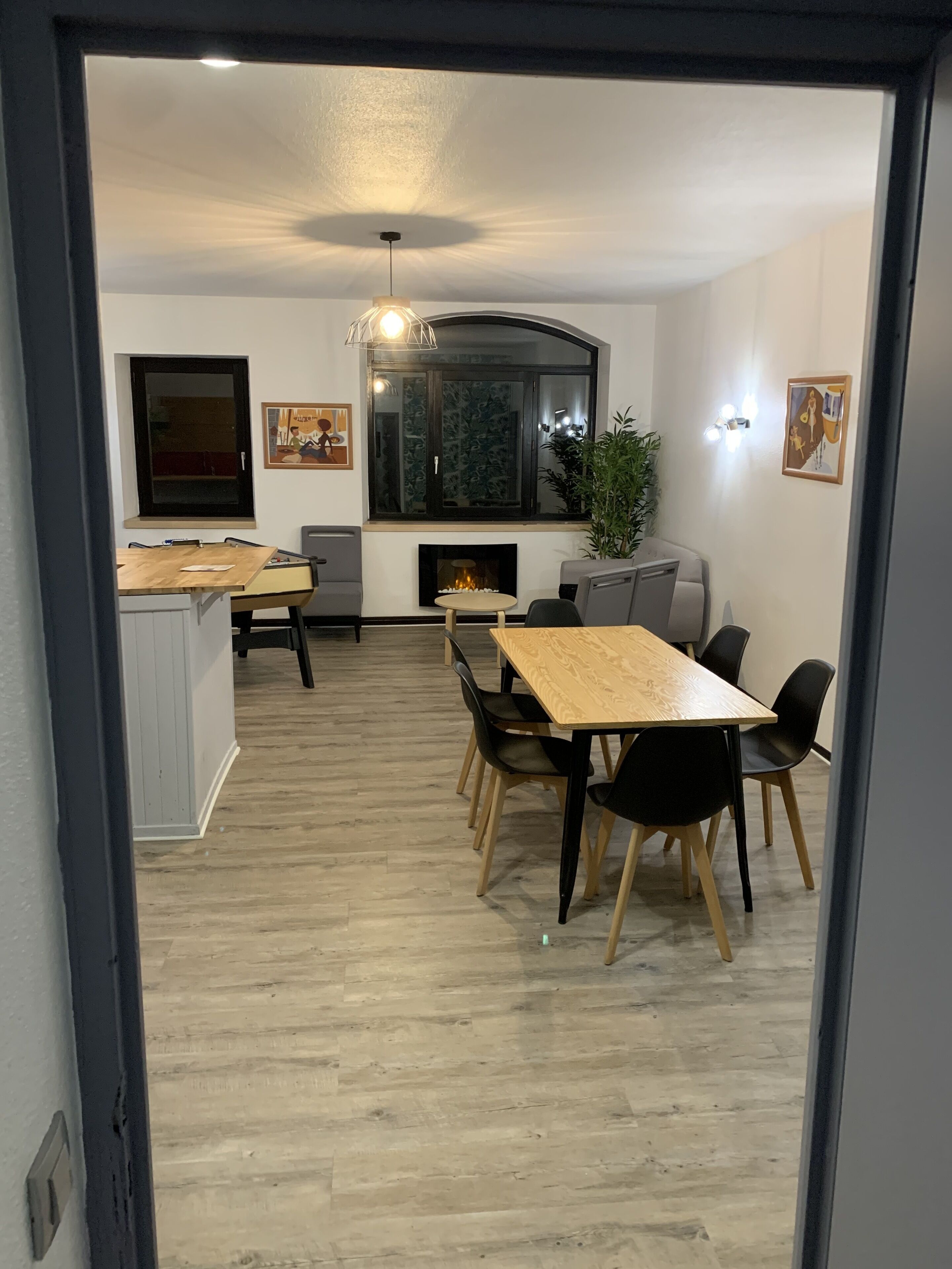 Un comedor moderno con una mesa y sillas de madera, una chimenea y obras de arte en las paredes.