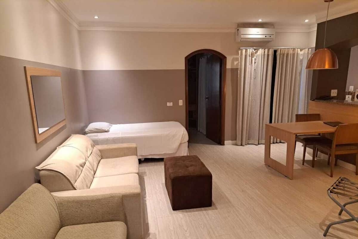 A hotel room with a bed, a sofa, a small table, and a desk.