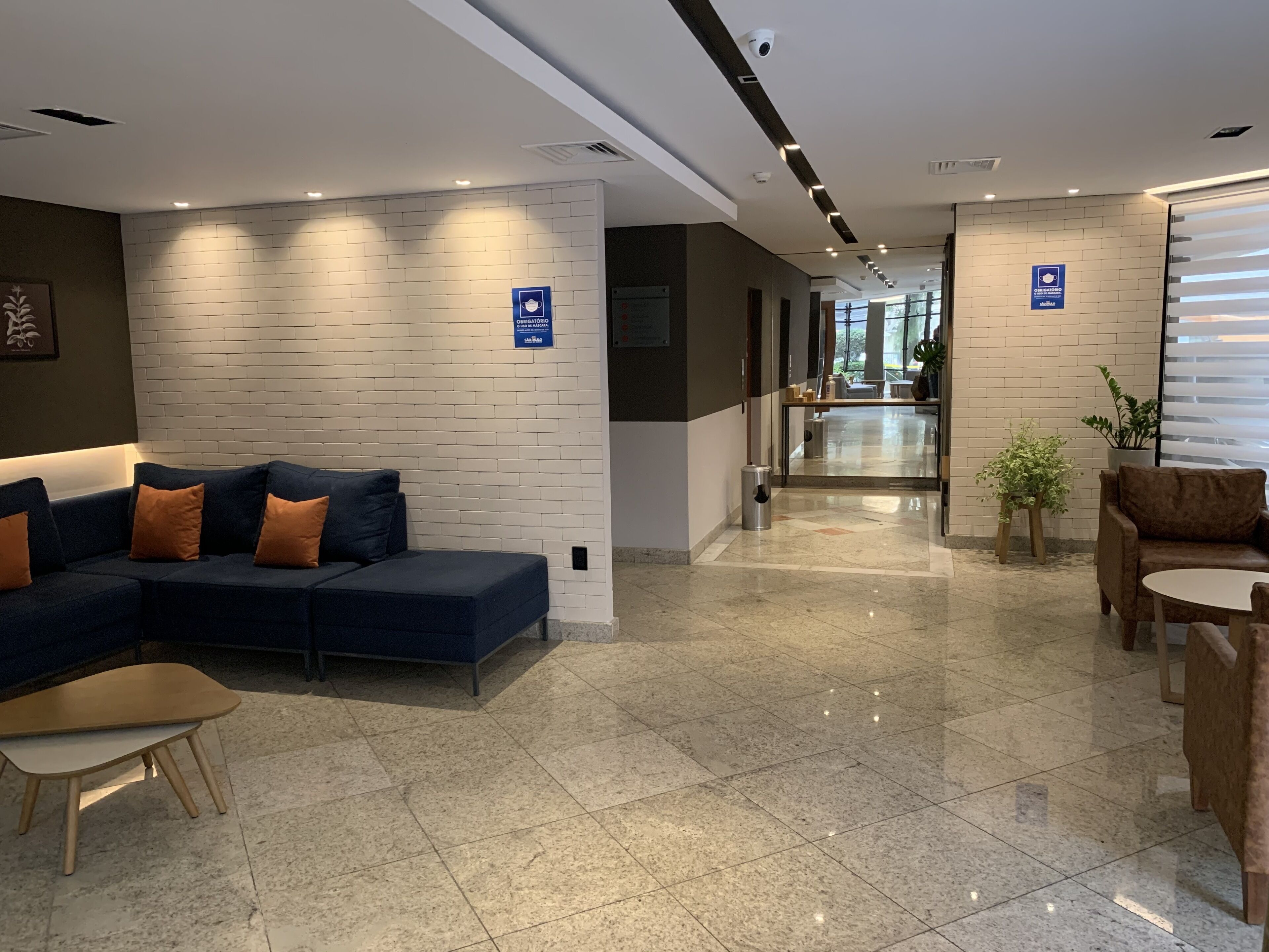 Un moderno vestíbulo de hotel con un sofá azul, una mesa de madera y una planta en maceta.
