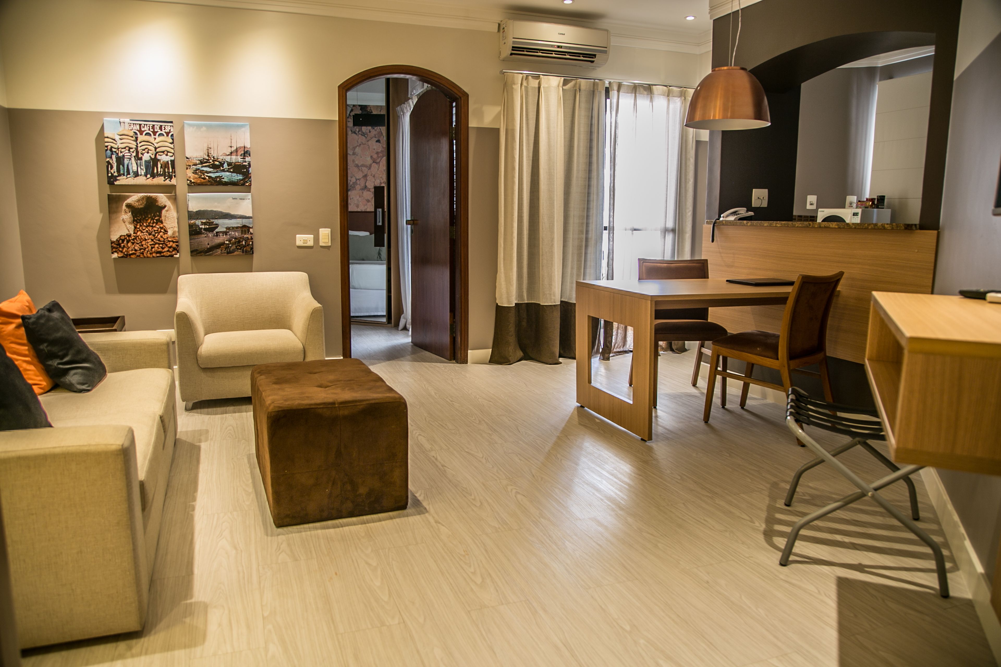 A modern hotel room with a living area, a dining table, and a kitchenette.