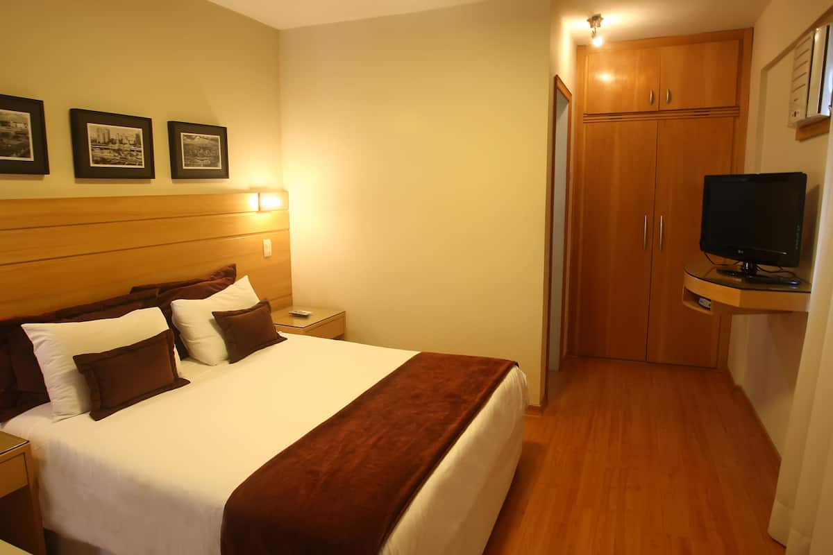 A hotel room with a bed, nightstands, a TV, a wardrobe, and framed pictures on the wall.