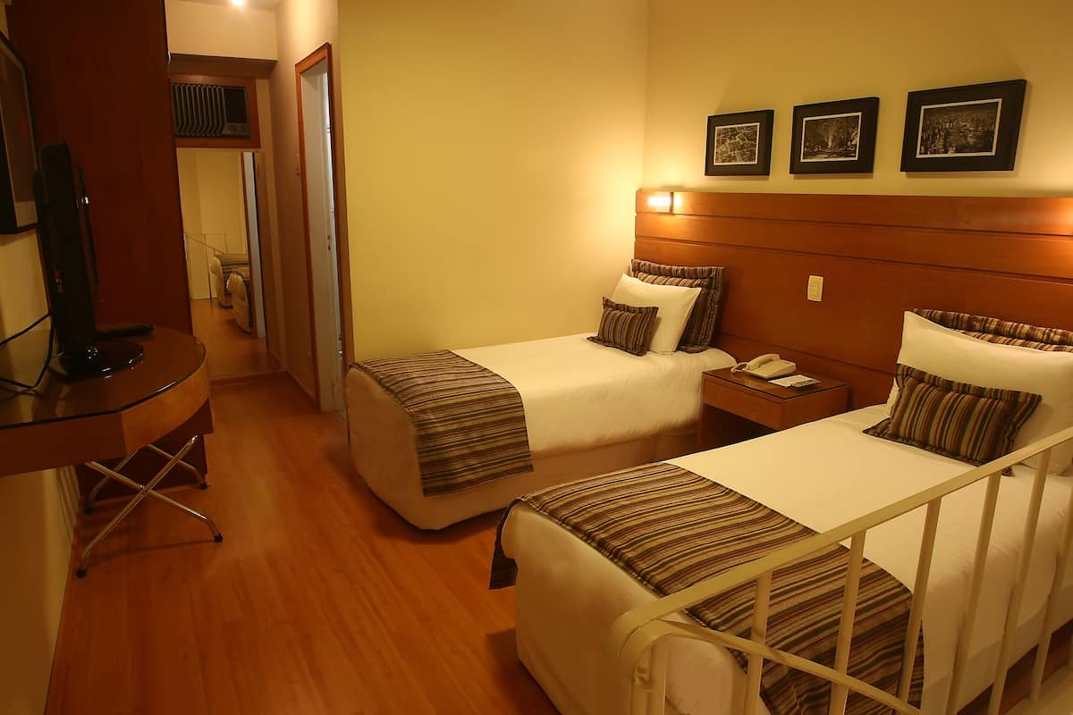 A hotel room with two beds, a desk with a computer, and a TV.